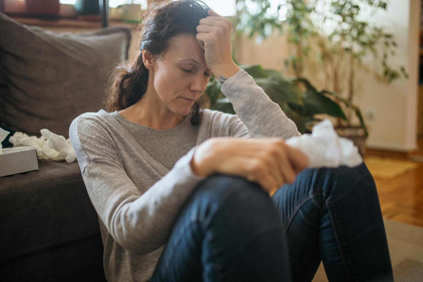 Adult woman sitting on floor and suffering from allergies or flu.