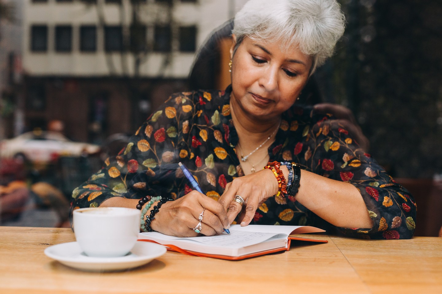 Middle Aged Woman Journaling In A Coffee Shop
