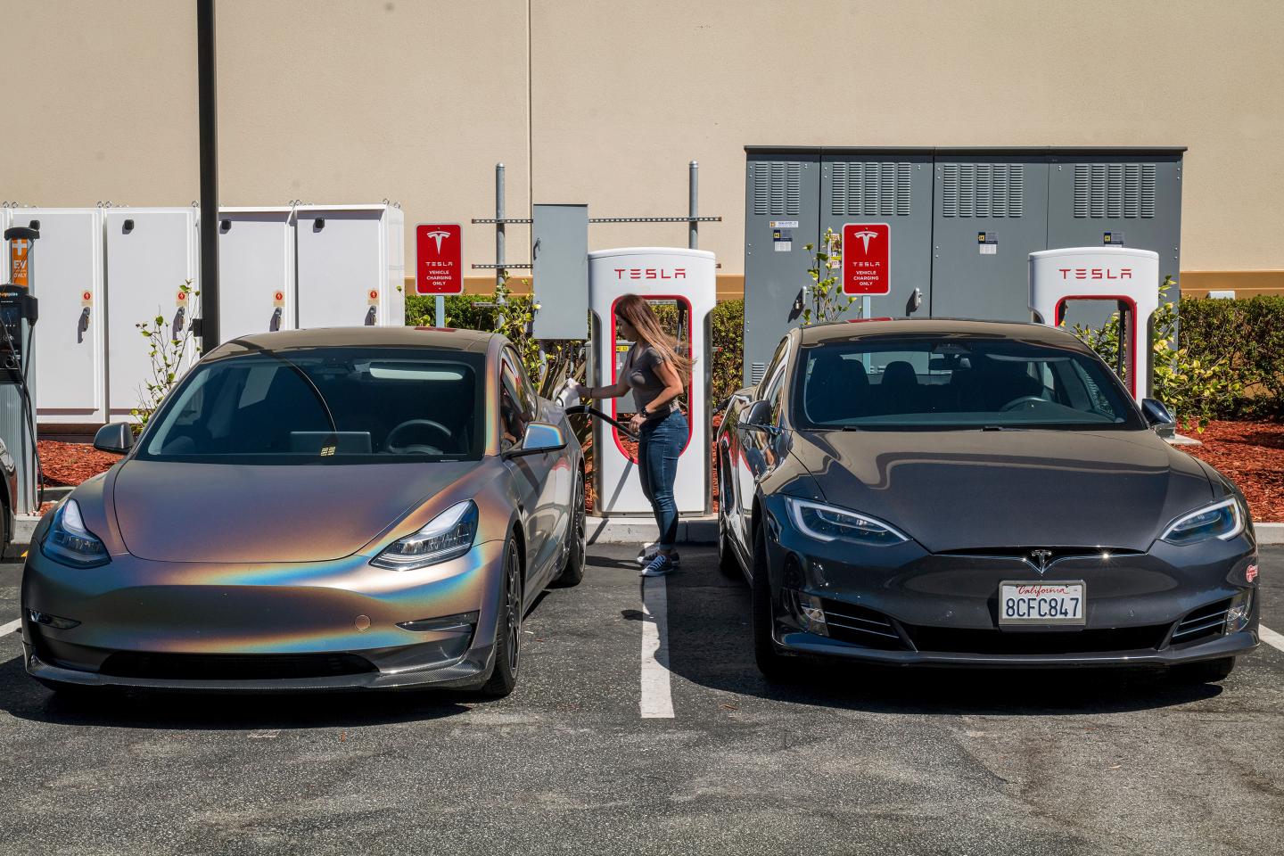 A person charges a Tesla Inc. vehicle at a charging station in San Mateo, California.