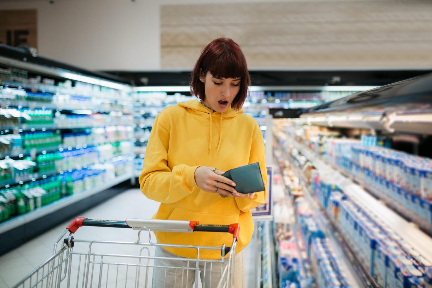 A woman is surprised by prices at the grocery store.