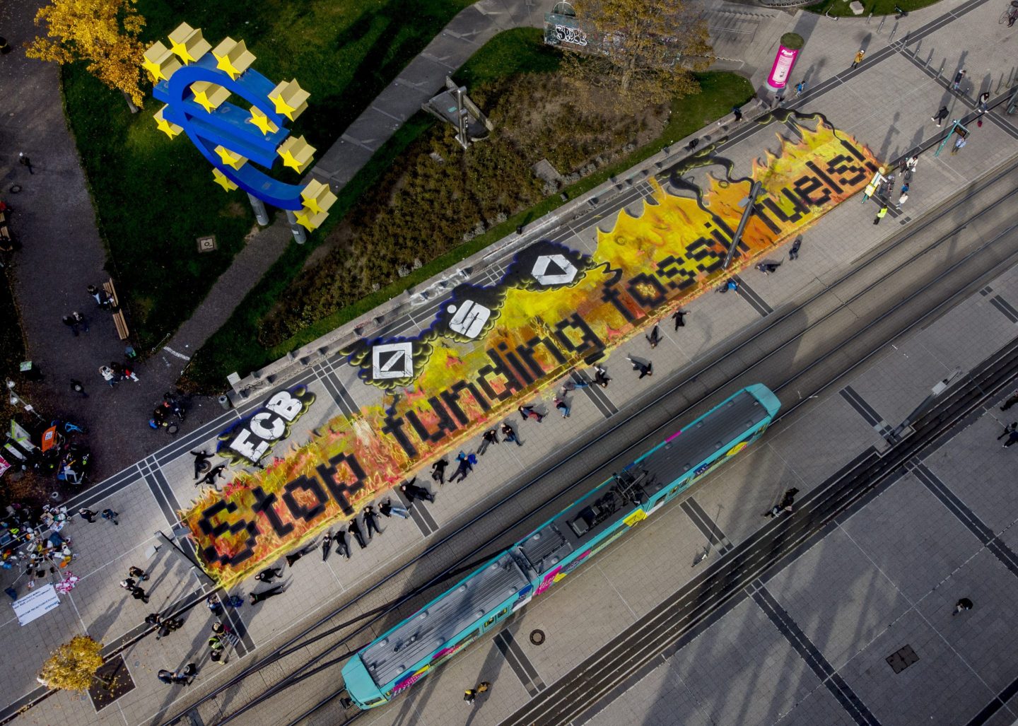 Climate activists lie after painting "stop funding fossil fuels" on the square in front of the Euro sign in Frankfurt, during a "Fridays for Future" event, Oct. 29, 2021.