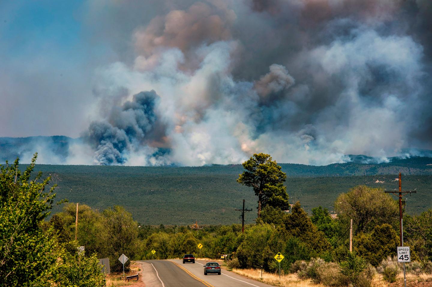 Smoke from a wildfire in New Mexico rises in the background of a landscape picture