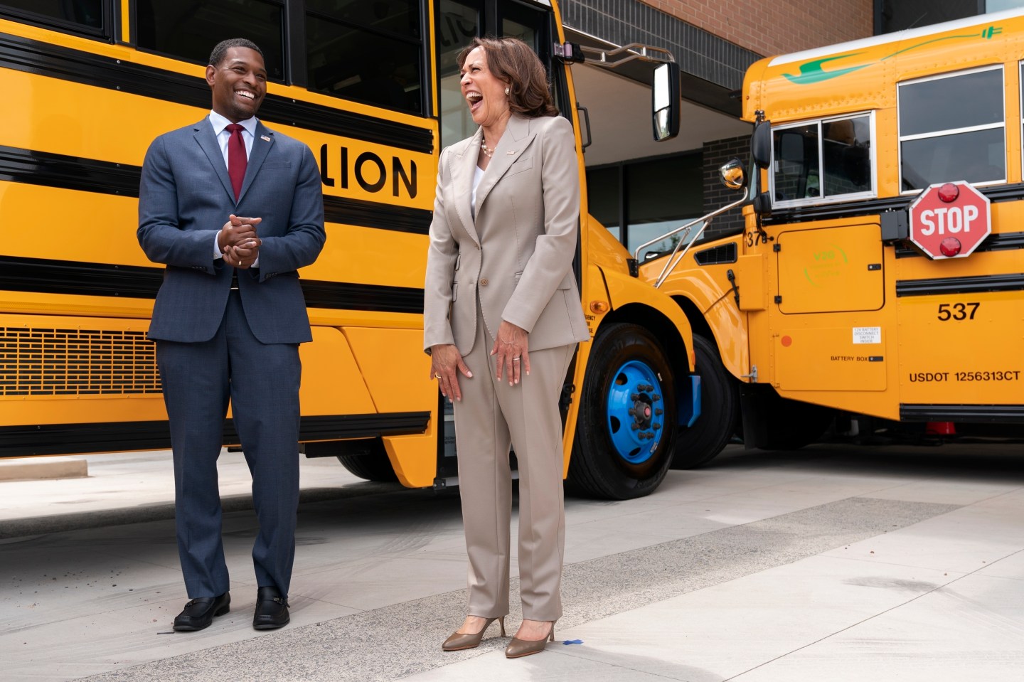 Vice President Kamala Harris, right, laughs with Environmental Protection Agency Administrator Michael Regan, during a tour of electric school buses at Meridian High School in Falls Church, Va., May 20, 2022. Nearly 400 school districts spanning all 50 states are receiving grants totaling nearly $1 billion to purchase nearly 2,500 "clean" school buses under a new federal program.
