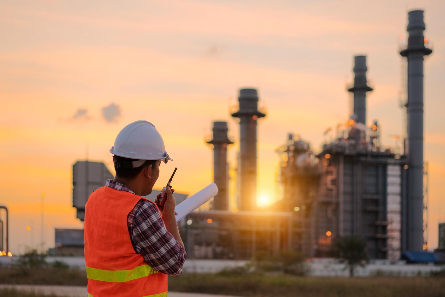 Shot of an engineer looking over a power plant at sunset