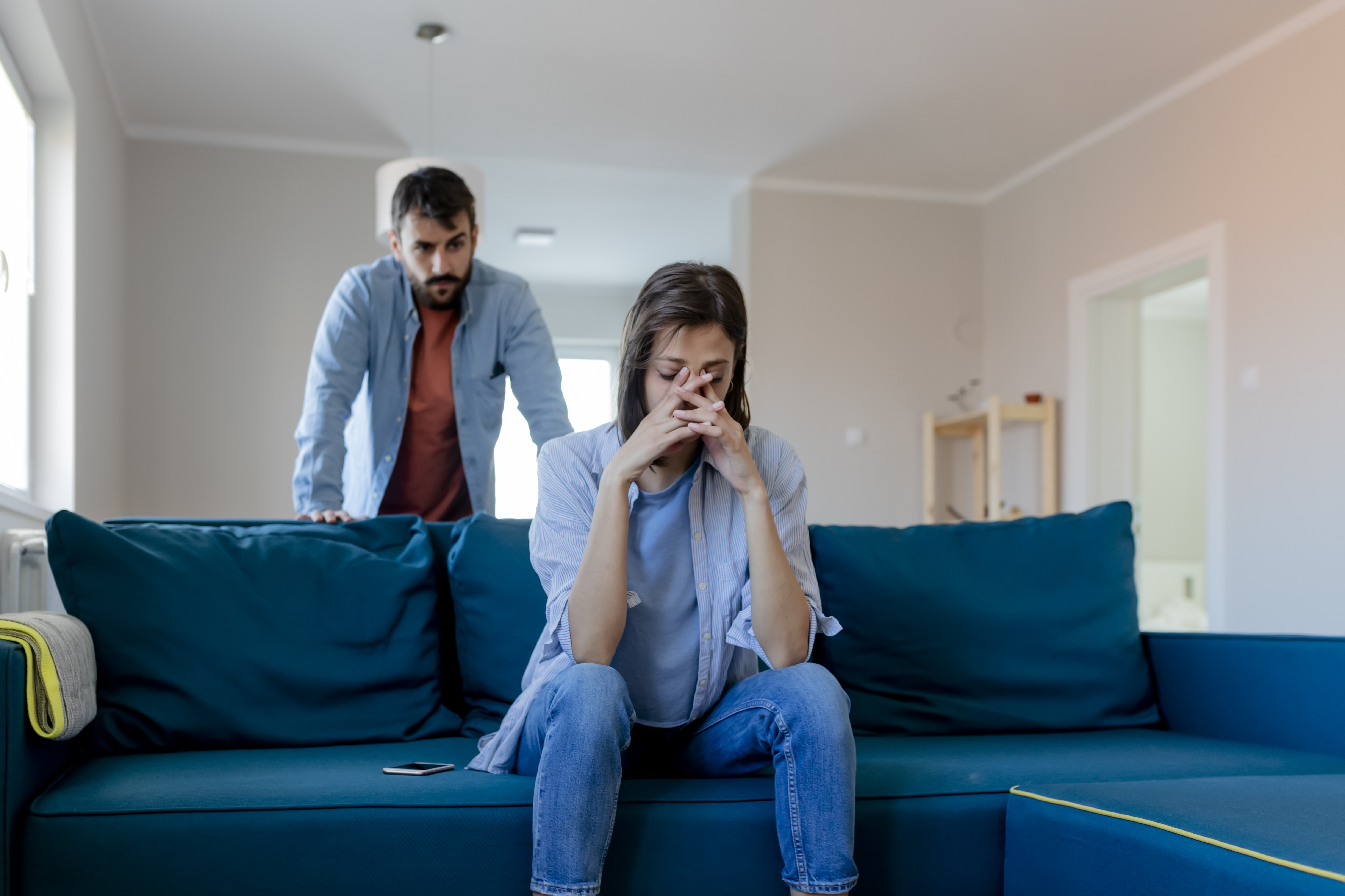 Man and woman looking sad and upset in a living room
