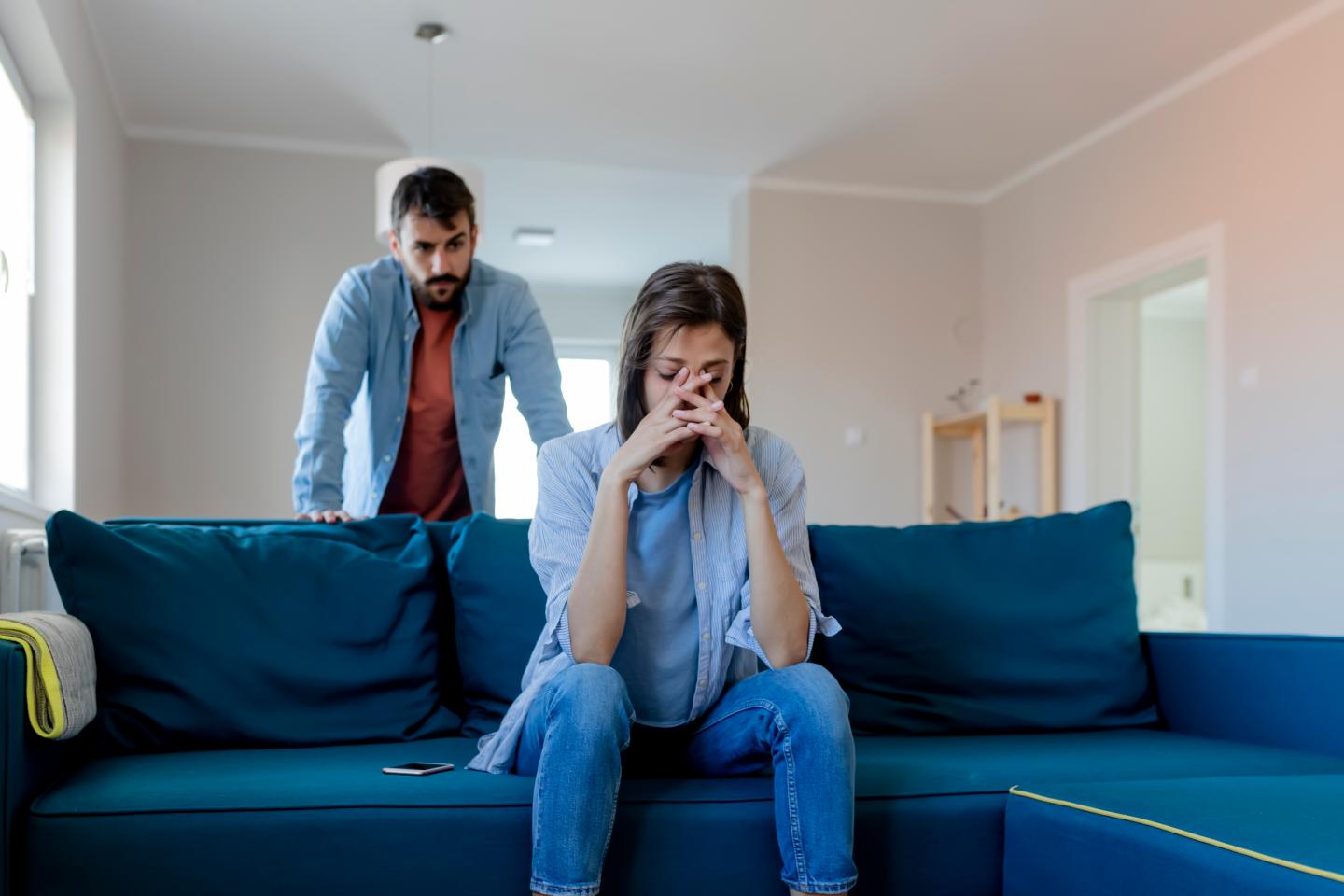 Man and woman looking sad and upset in a living room
