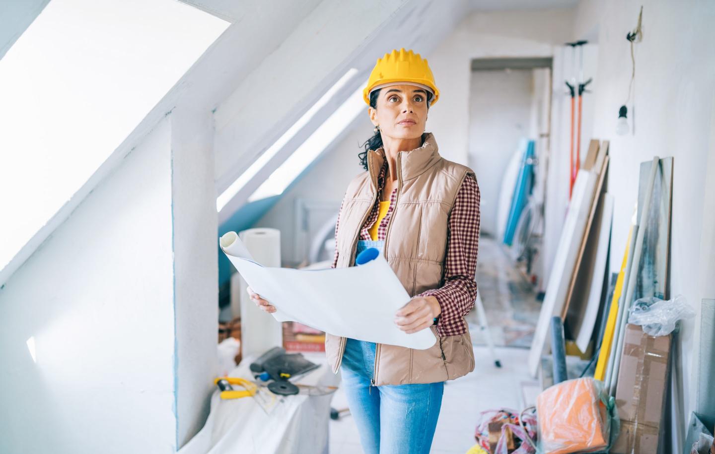 Female architect looking at blueprints on construction site