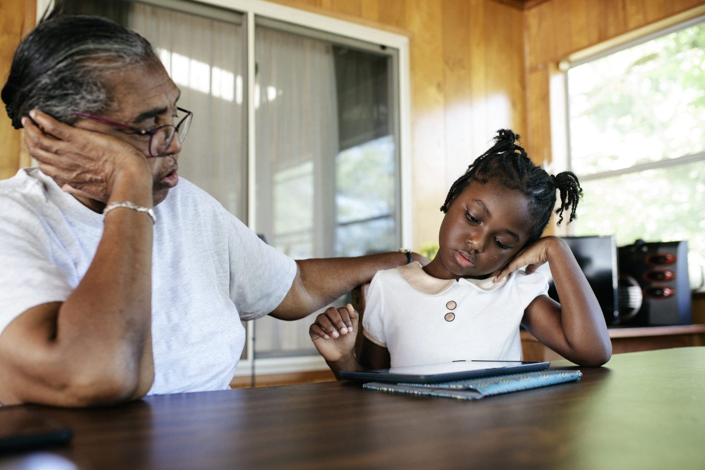 Black Grandmother and granddaughter at home working on a digital tablet