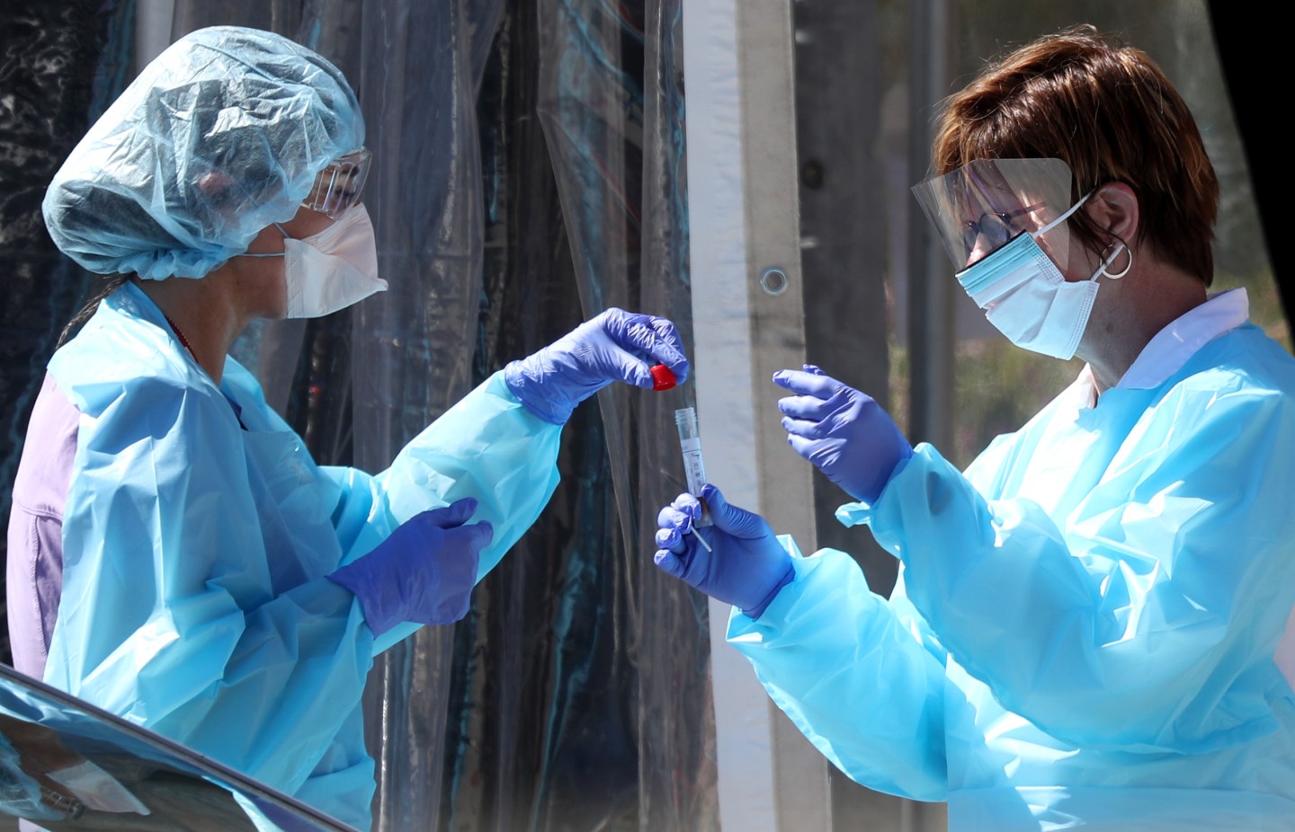 Medical personnel wearing protective clothing secure a sample from a person at a drive-thru Coronavirus testing station in San Francisco.