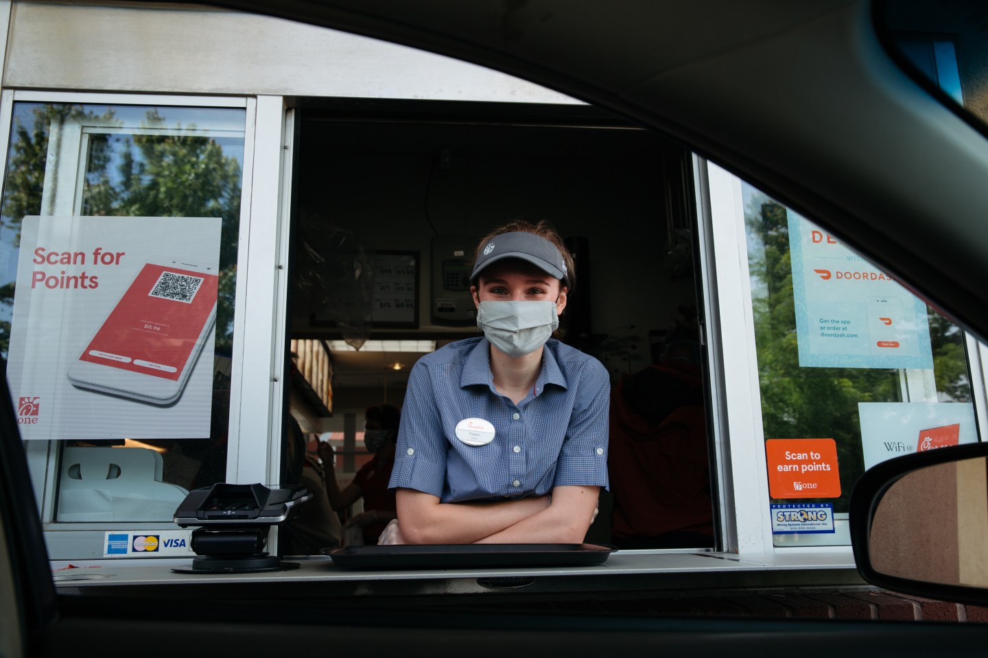 An employee wears a protective mask while working the drive-thru window of a Chick-fil-A Inc. restaurant in Bentonville, Arkansas.