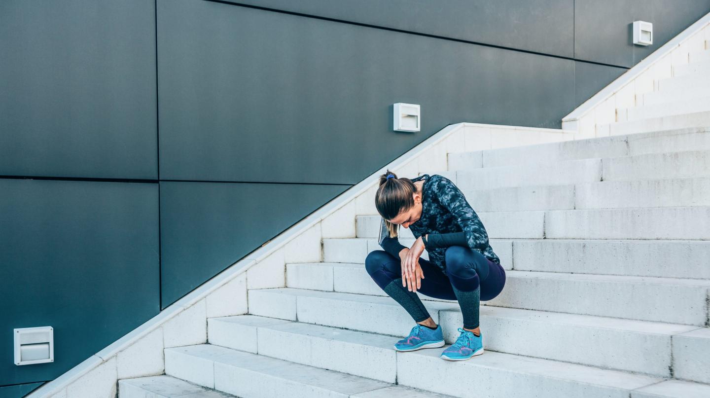 Exhausted runner resting on the stairs after exercise.