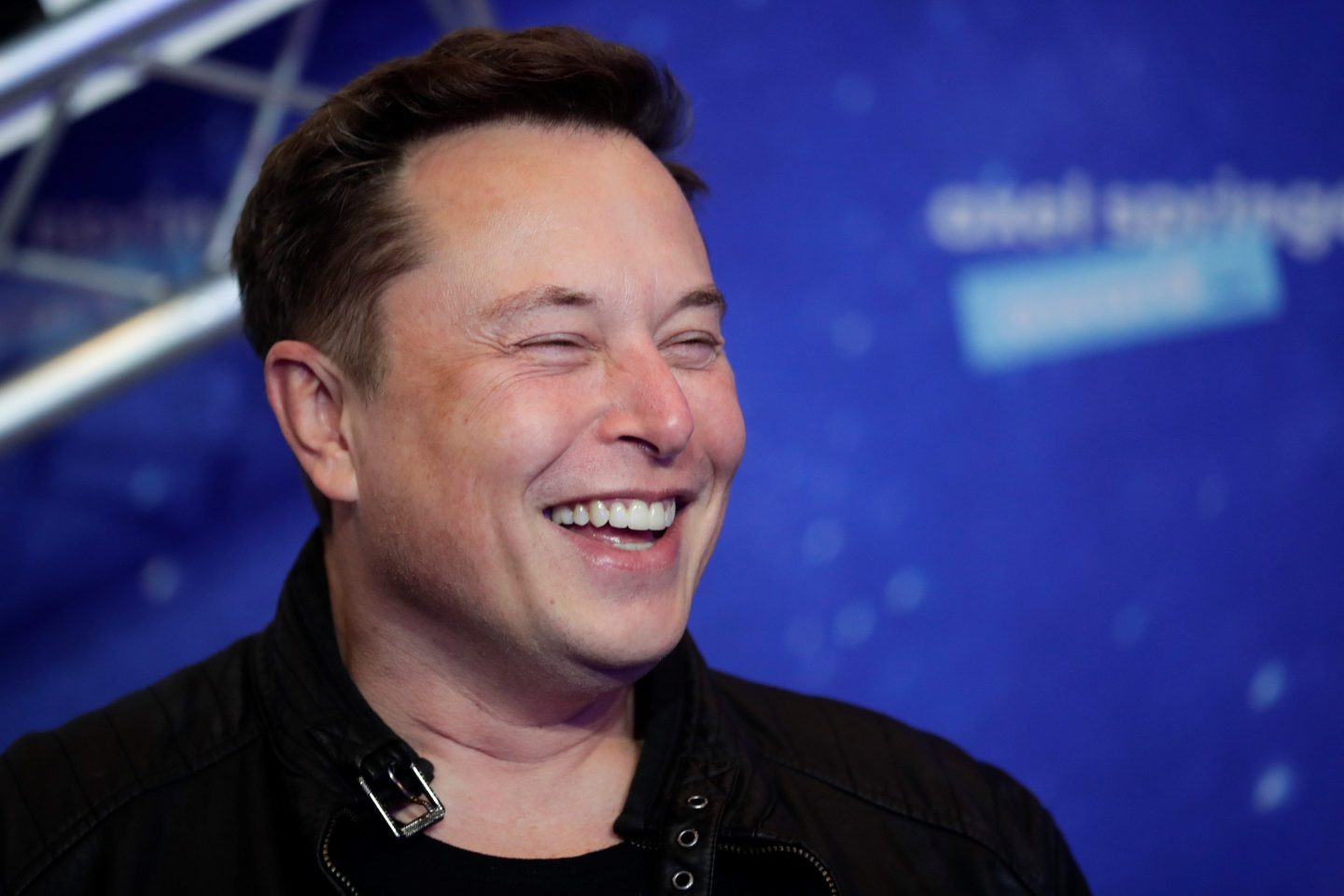 Elon Musk laughs as he arrives on the red carpet