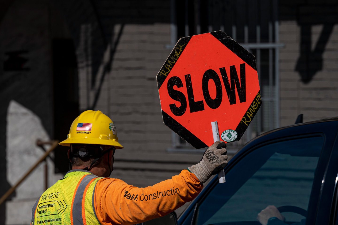 A contractor holds a sign reading "Slow" on Van Ness Boulevard in San Francisco, California, U.S., on Monday, March 22, 2021.