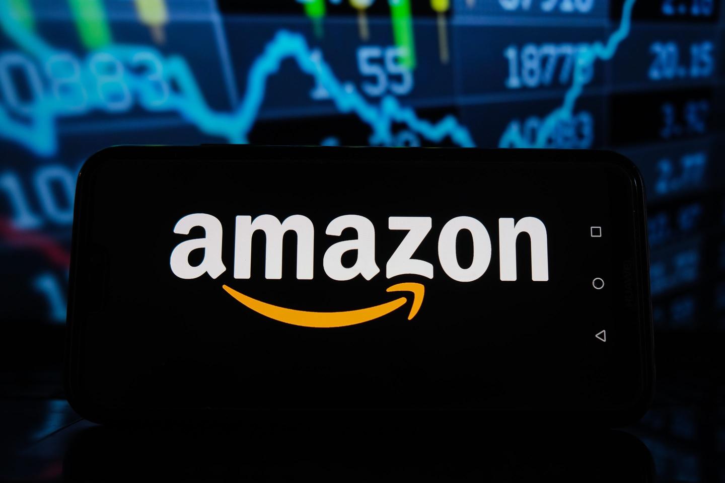 A phone with an Amazon logo in front of a stock market chart