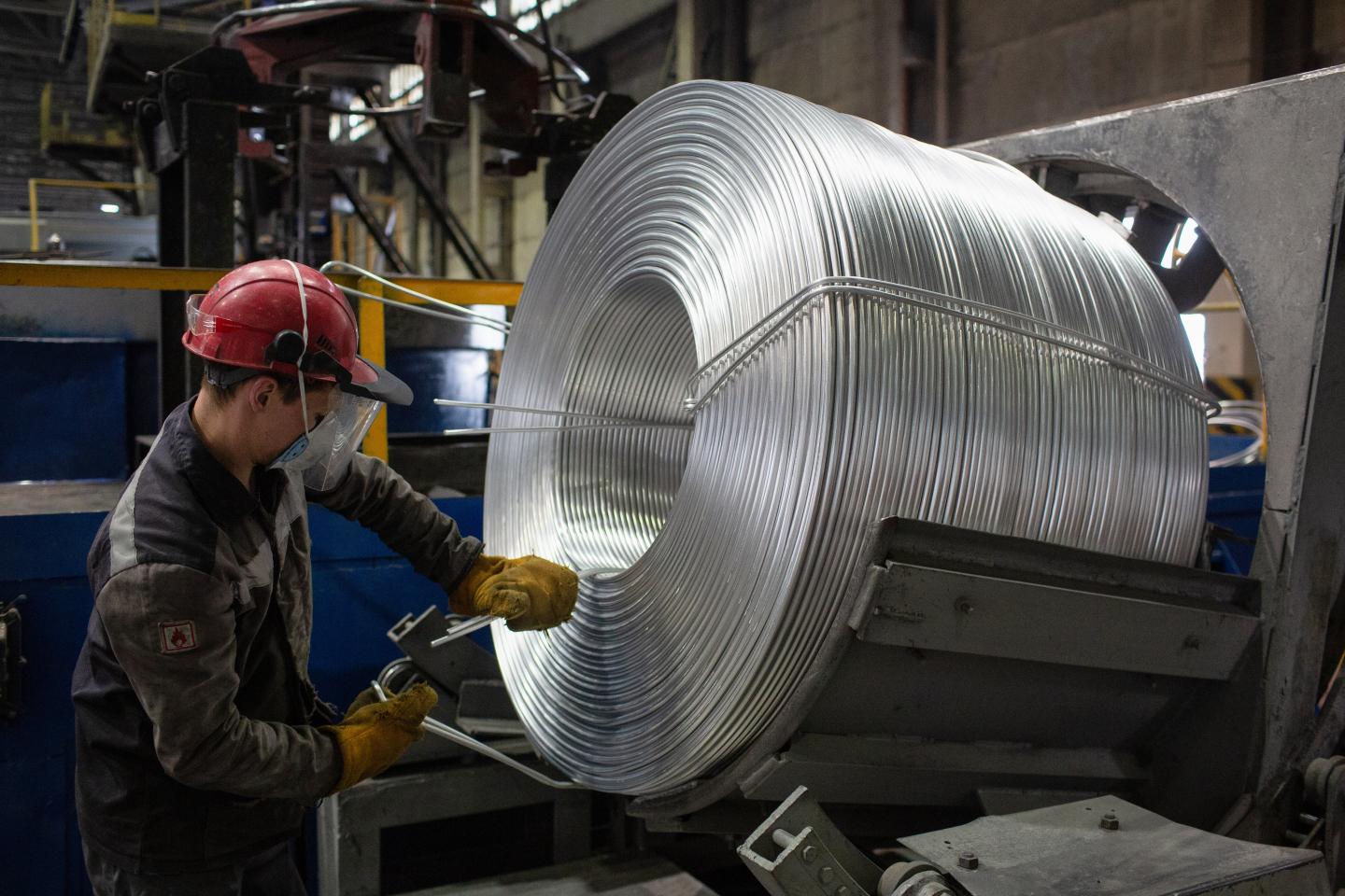 A worker tightens a binding around a coil of aluminum wire at Rusal's aluminium smelting plant in Shelekhov, Russia.