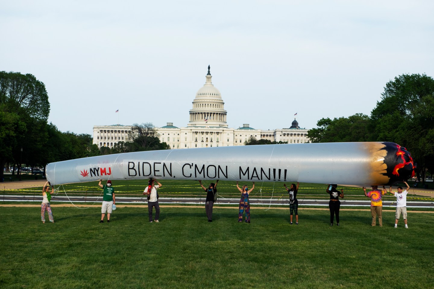 A group of people hold up a 51 blow-up joint on the National Mall.