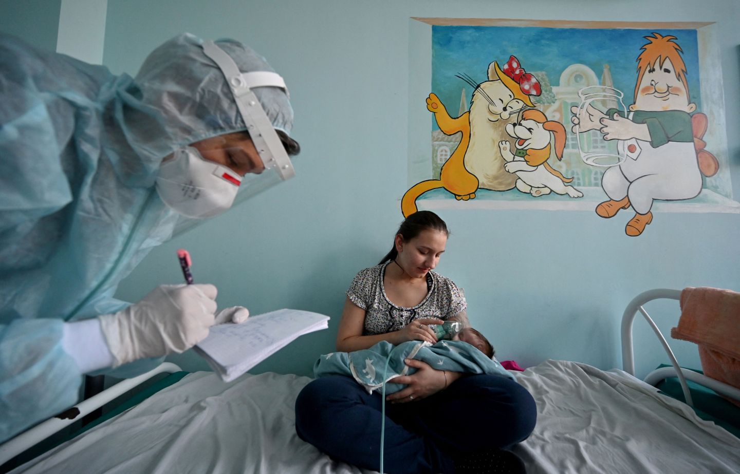 A woman holds an oxygen mask over the face of her baby suffering from COVID-19 in the ward of a children’s hospital in Kyiv, on Nov. 16, 2021.