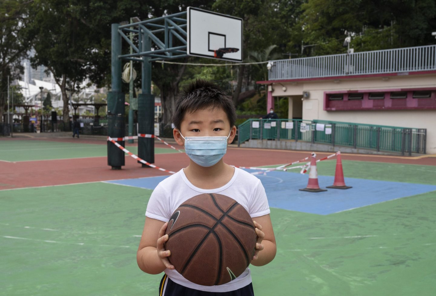A child holds a basketball at a closed playground in Hong Kong