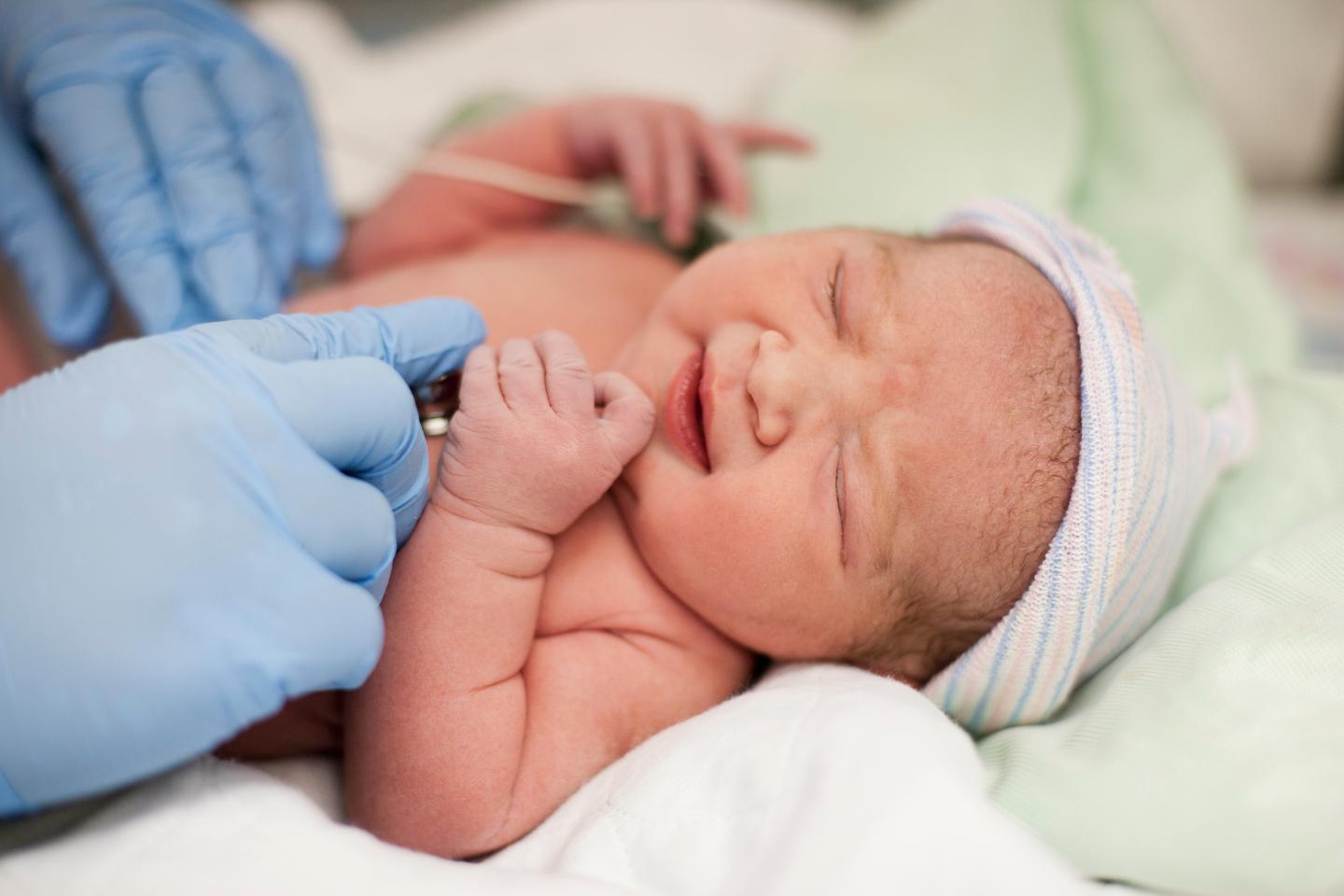 Doctor listening to newborn baby's heartbeat