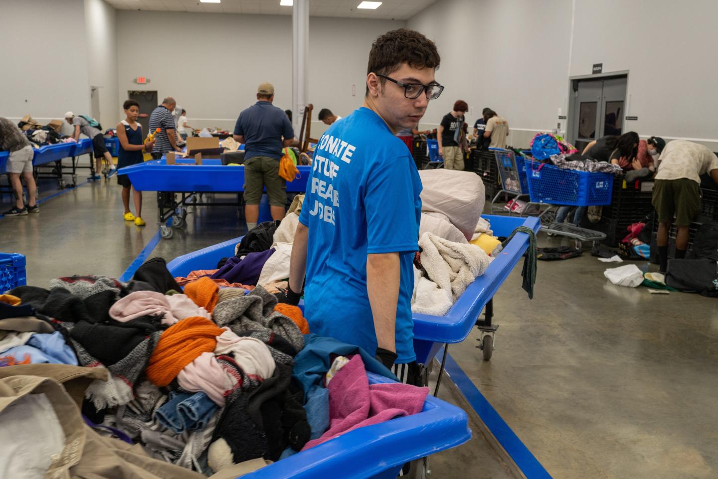 A Goodwill employee next to a pile of clothes.
