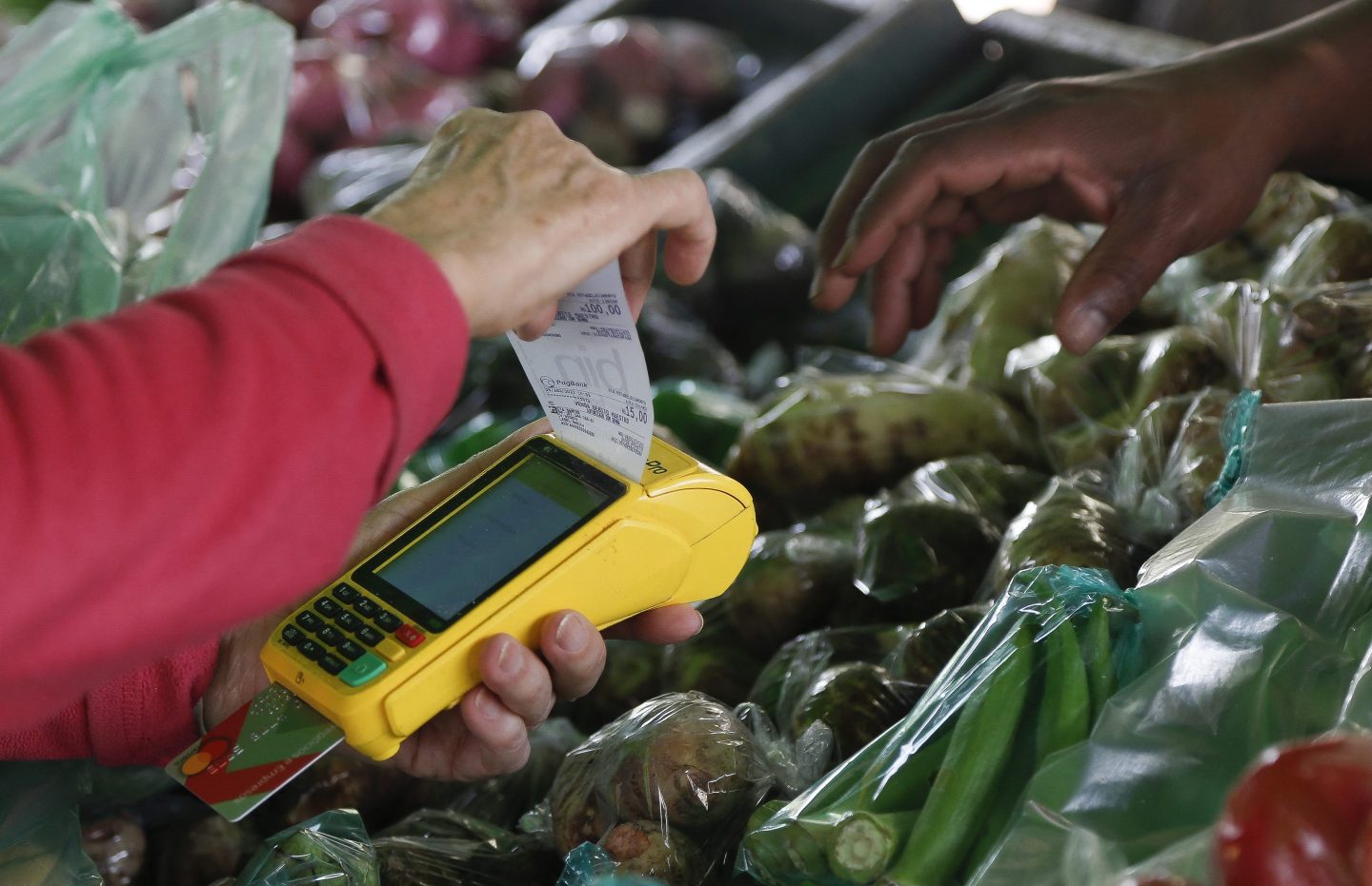 A customer pays by card at a vegetables stall in the street market in Sao Paulo, Brazil, on August 25, 2022. - About 53% of Brazilians say the economic situation -high inflation, unemployment and food insecurity- will determine their vote in the upcoming October 2 election. (Photo by Miguel SCHINCARIOL / AFP) (Photo by MIGUEL SCHINCARIOL/AFP via Getty Images)