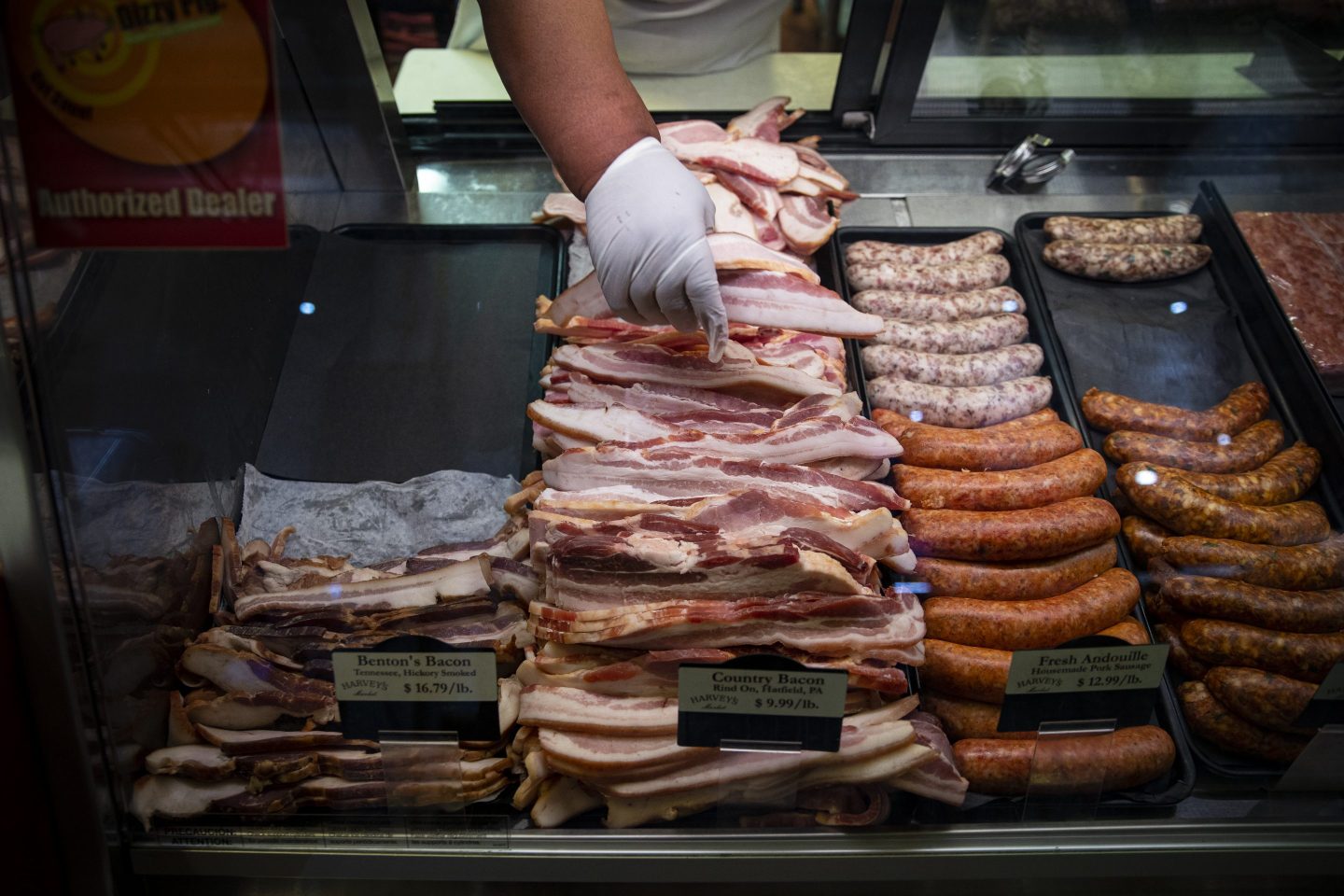 A worker adjusts cuts of bacon for sale at a butcher shop