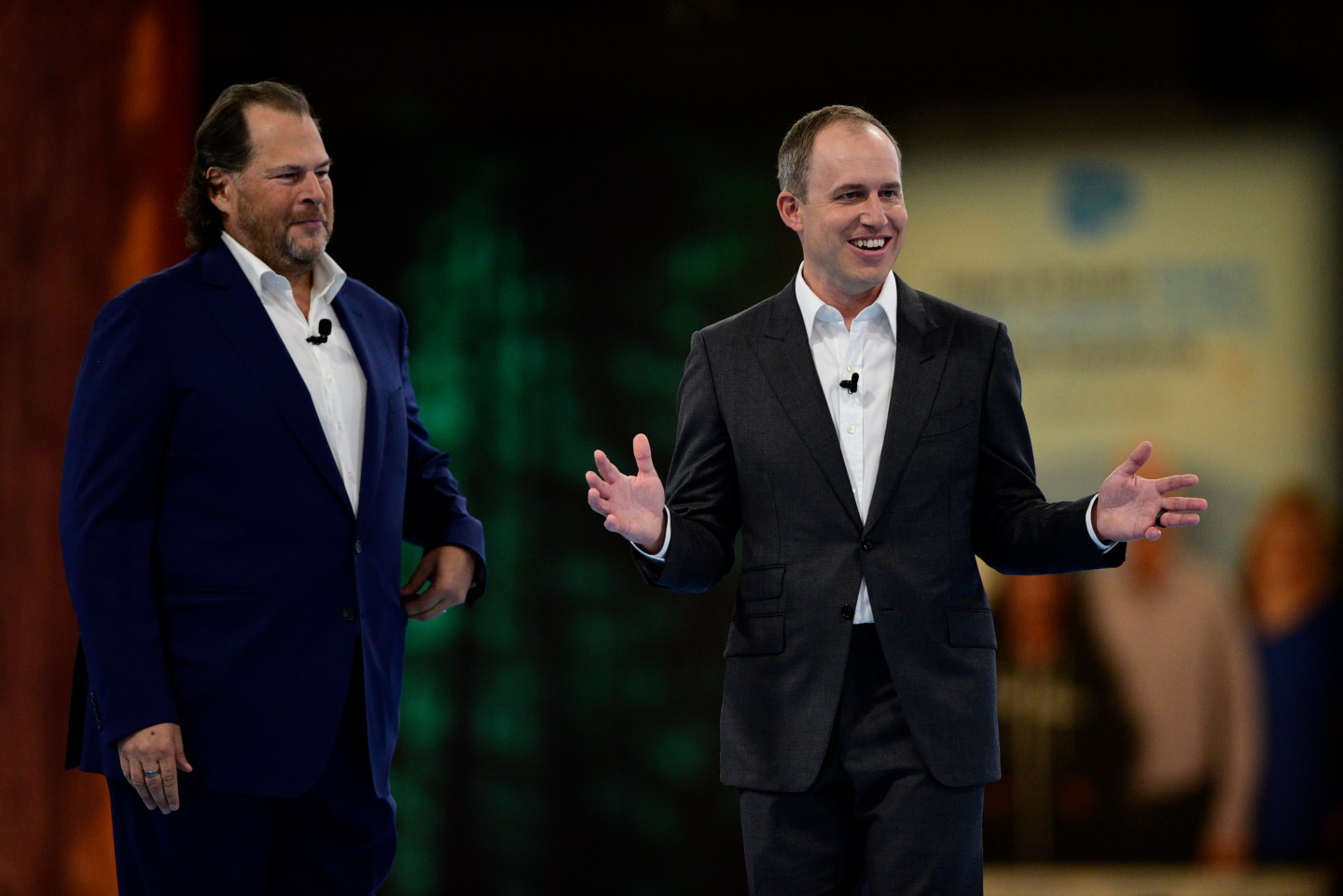 Co-chief executives Marc Benioff and Bret Taylor stand on stage giving a keynote at Dreamforce. Both are wearing black suits,