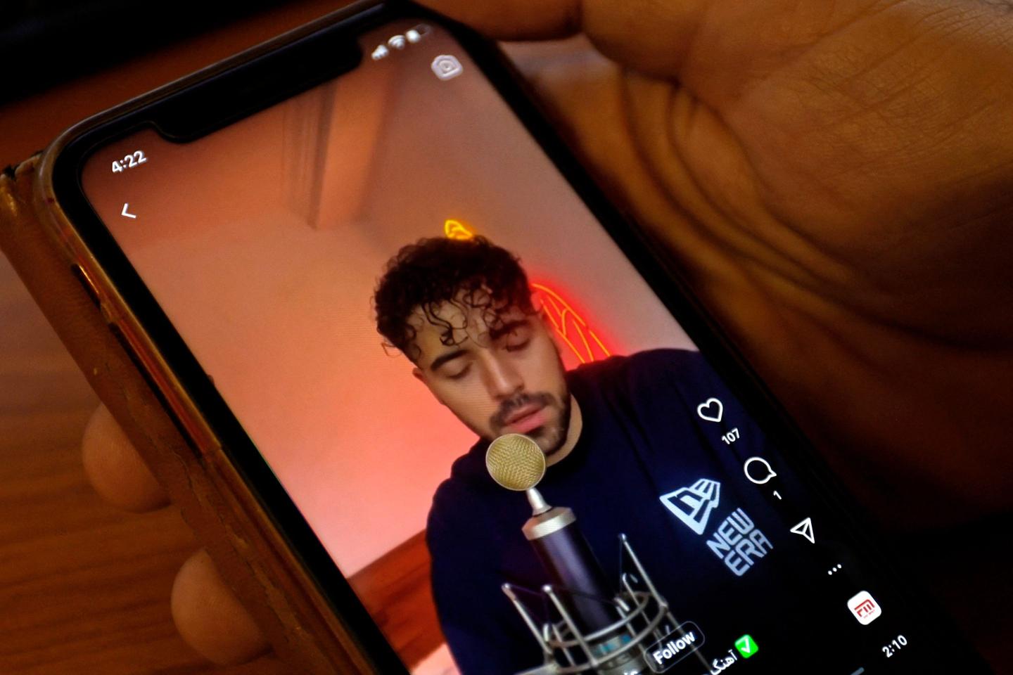 A man sings on a microphone in a video pictured on a cell phone.