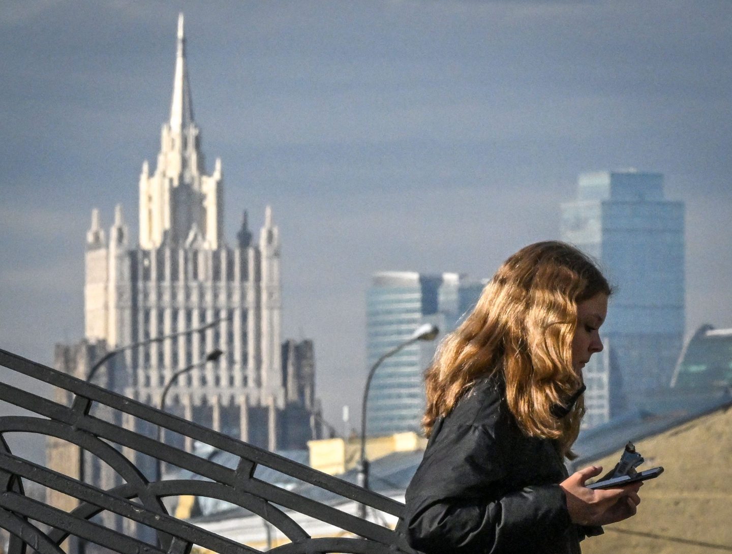 A woman walks on a bridge in front of skyscrapers of Moscow's International Business Centre (Moskva City) and the Russian Foreign Ministry building (L) in Moscow on Oct. 13th.