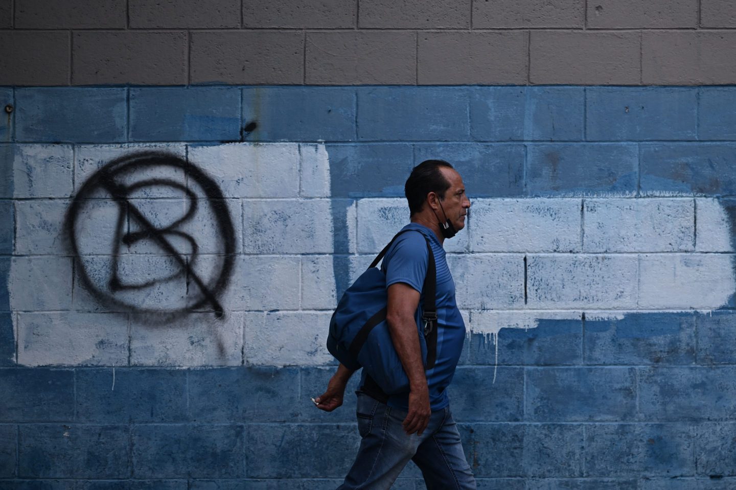 A man walks past a wall painted with an anti-Bitcoin protest symbol in San Salvador on Oct. 18.