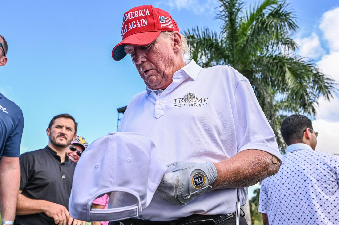 Former US President Donald Trump signs autographs as he walks off the seventh green