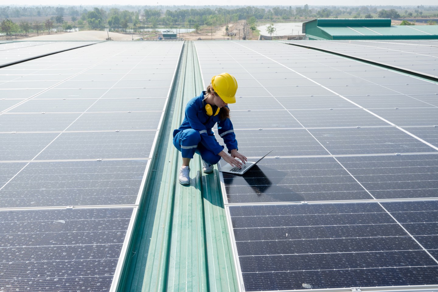 Woman engineer working on a computer next to a solar panel array