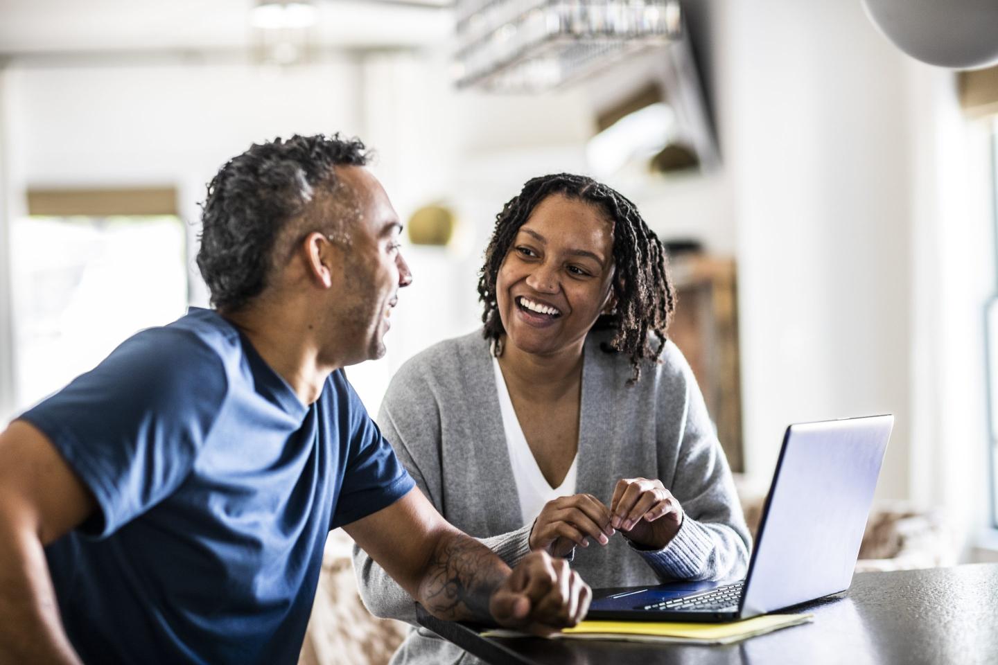 Husband and wife using laptop at home