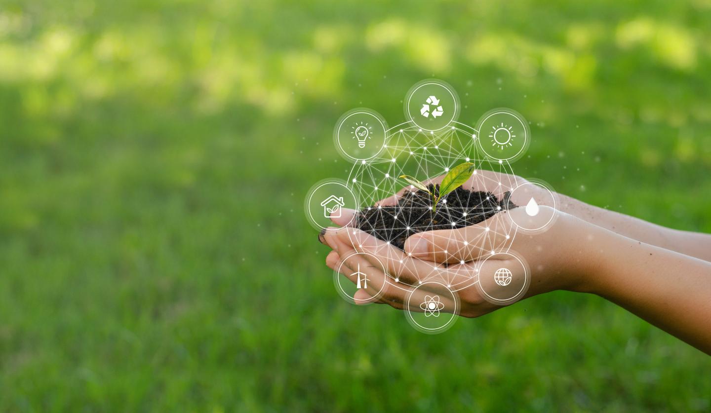 Hands holding soil with symbols of ESG surrounding it
