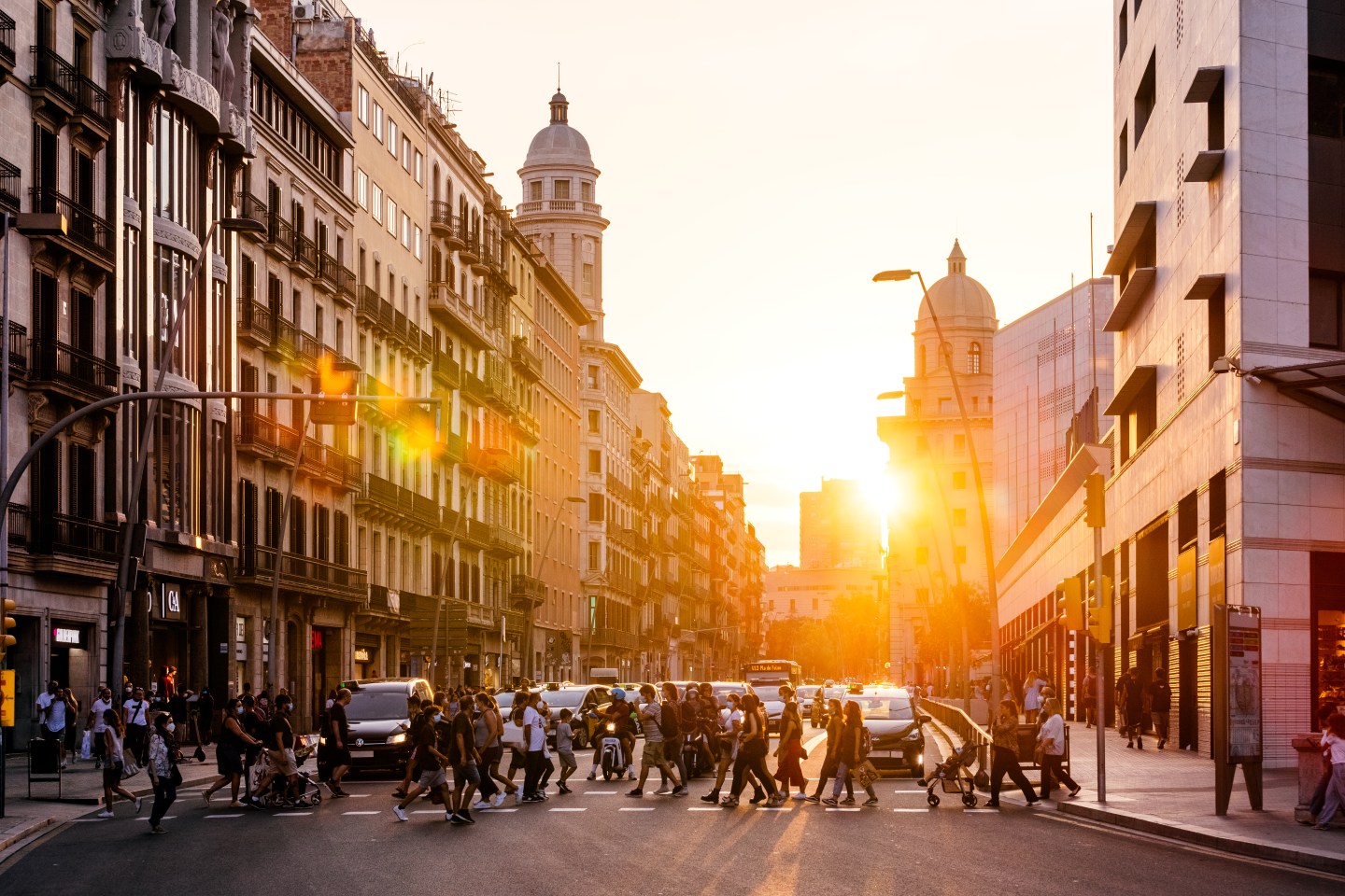 People crossing the street in Barcelona at sunset.