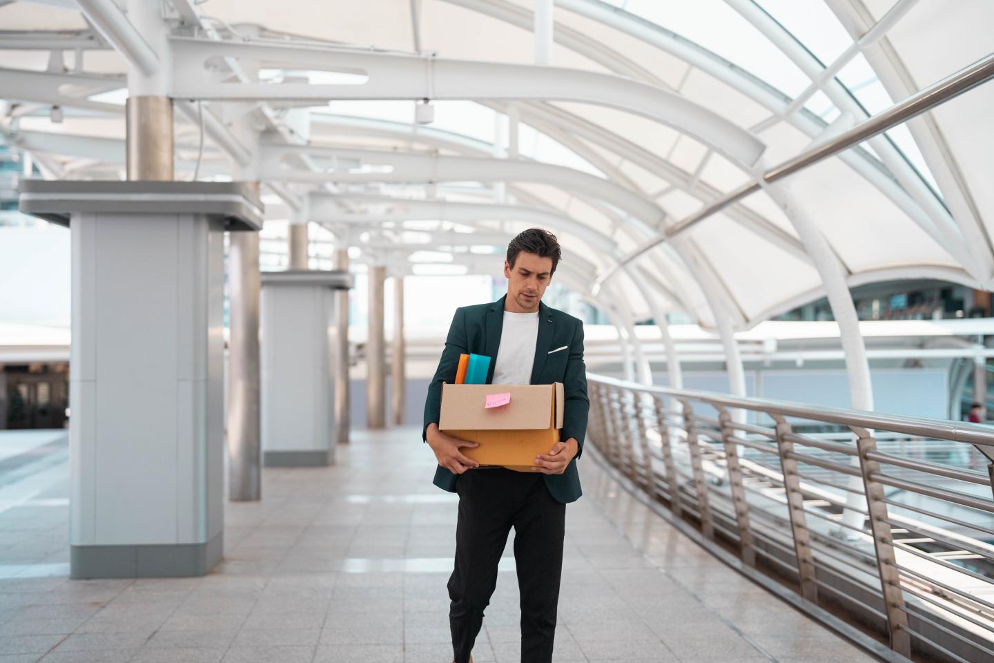 Shot of man with a sad look walking holding a box of items