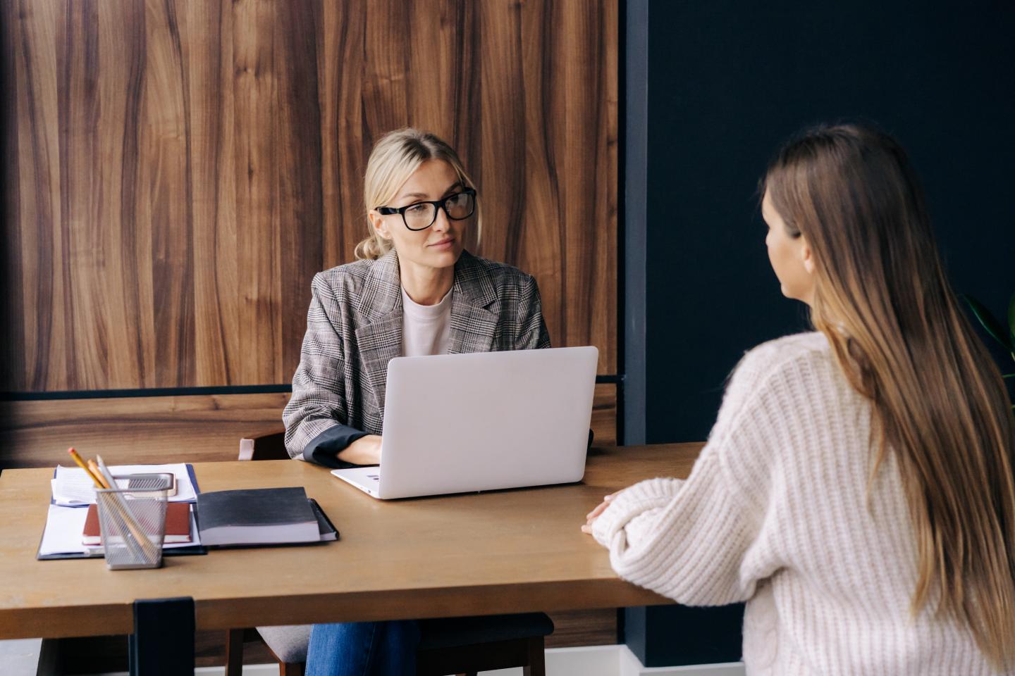 Two women talk in a one-on-one office meeting.