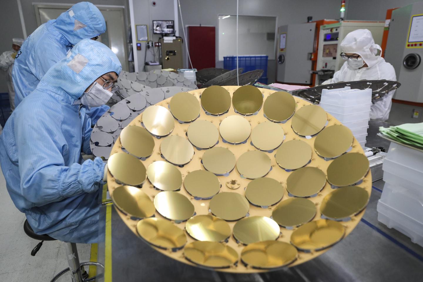 Chinese employees in protective gear work on silicon wafers