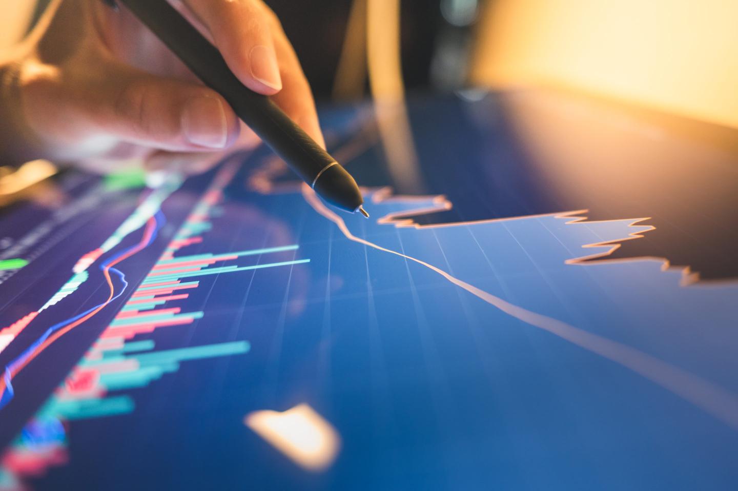 A trader looks at a line and bar graph of financial data