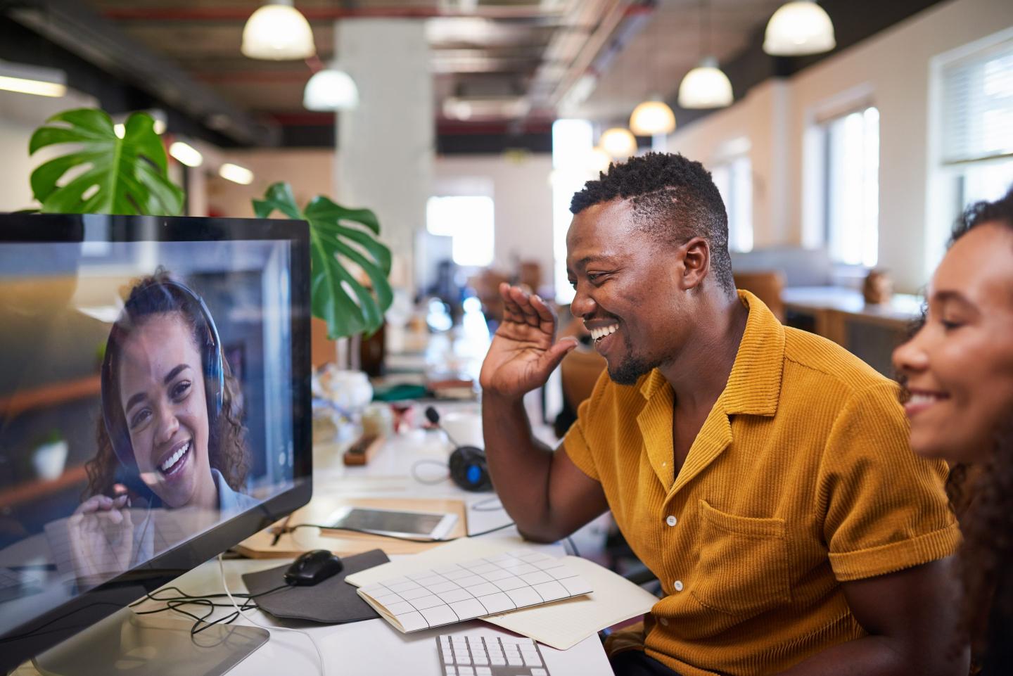 Two in-office workers chat with a remote worker over Zoom.