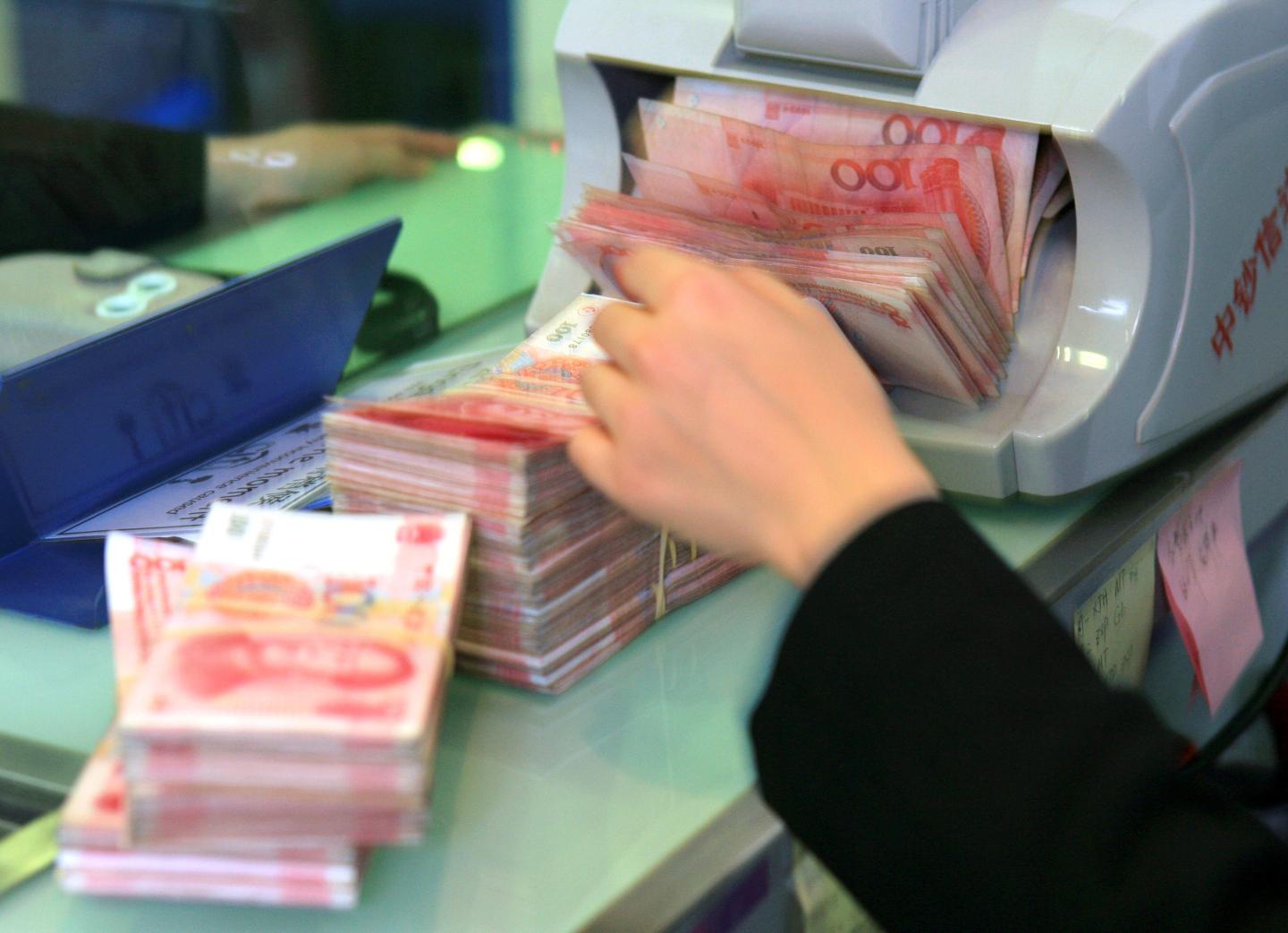 SHANGHAI, CHINA - February 01: A teller counts Chinese Yuan banknotes at a bank on February 1, 2008 in Shanghai, China. The Chinese Yuan is known locally as the RMB, or renminbi, which means 'the money of the people'. (Photo by Lucas Schifres/Getty Images)