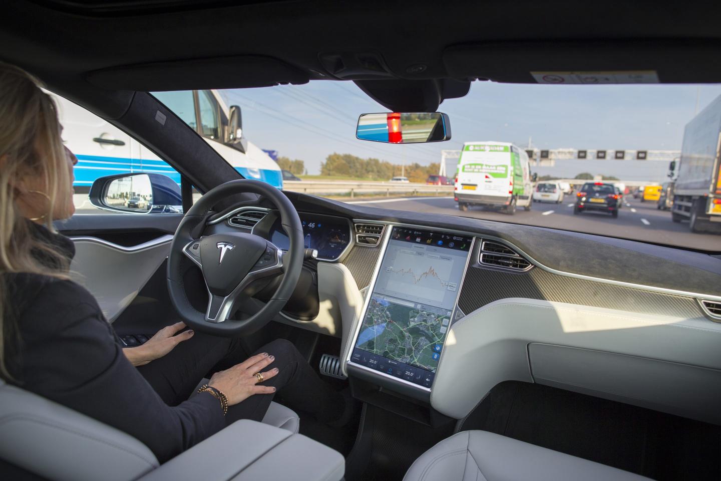 An employee drives a Tesla Motors Inc. Model S electric automobile, equipped with Autopilot hardware and software, hands-free on a highway
