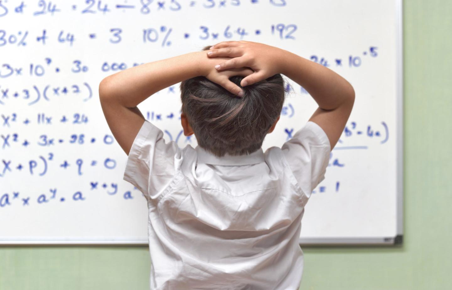 JUNIOR PUPIL AMAZED BY MATHS ON CLASSROOM WHITEBOARD