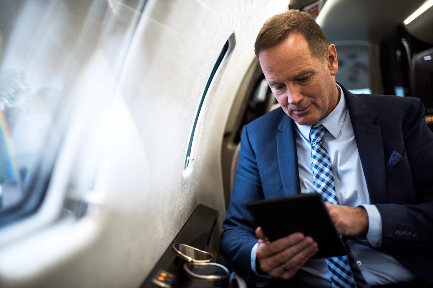 A man works from a tablet in a plane.
