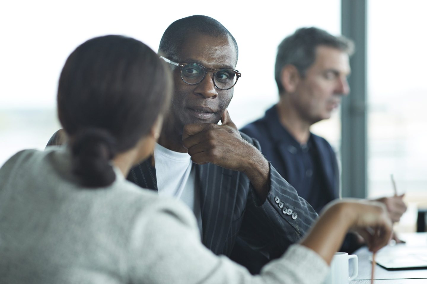 Business man smiling at a colleague in large modern meeting room