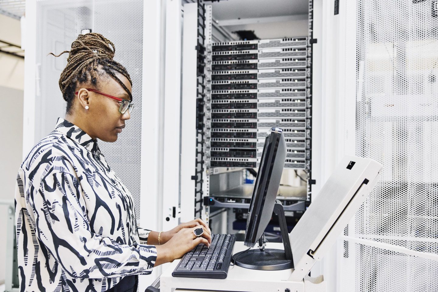 A business woman uses computer in front of a server