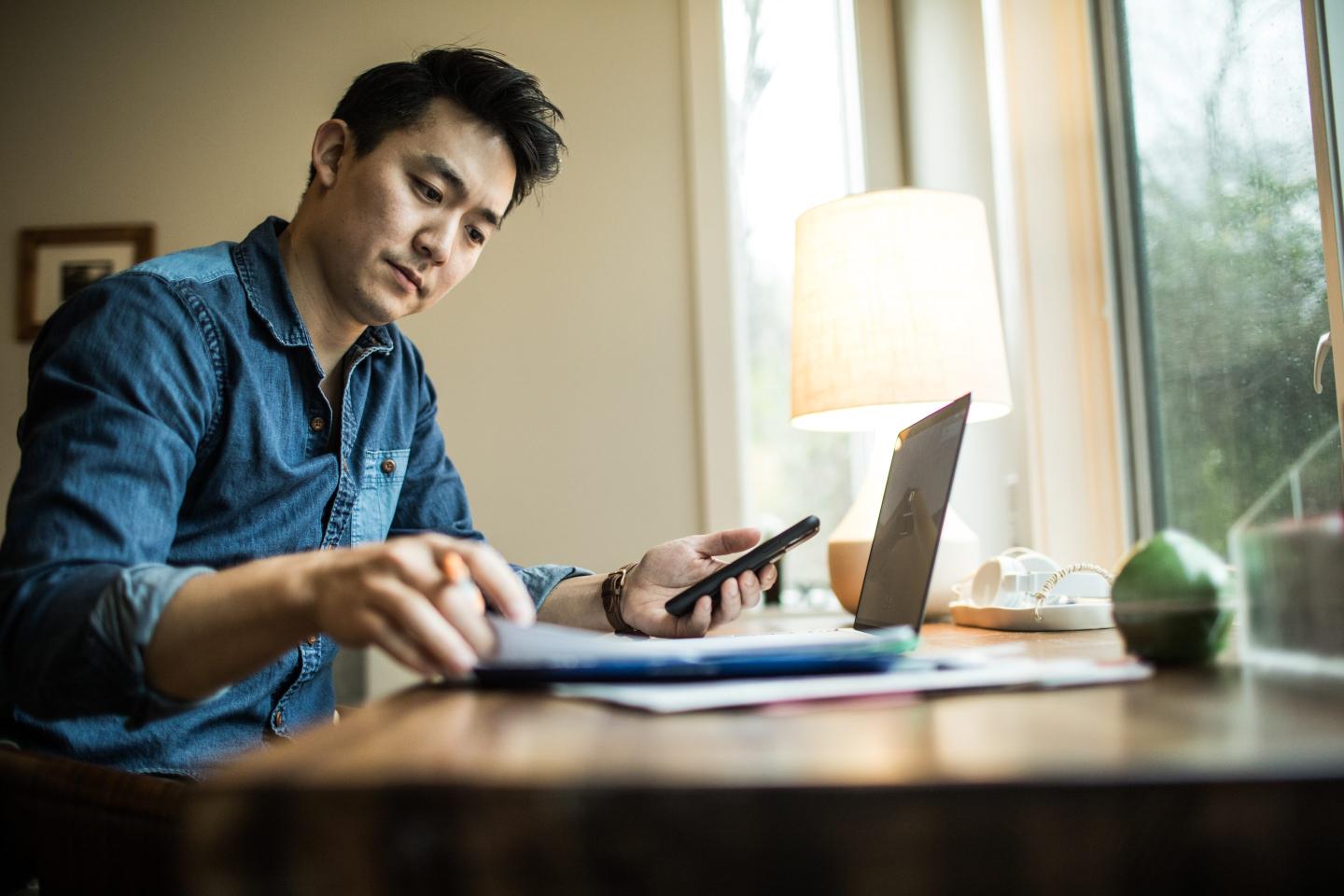 A man in his early 30s works in his home office.