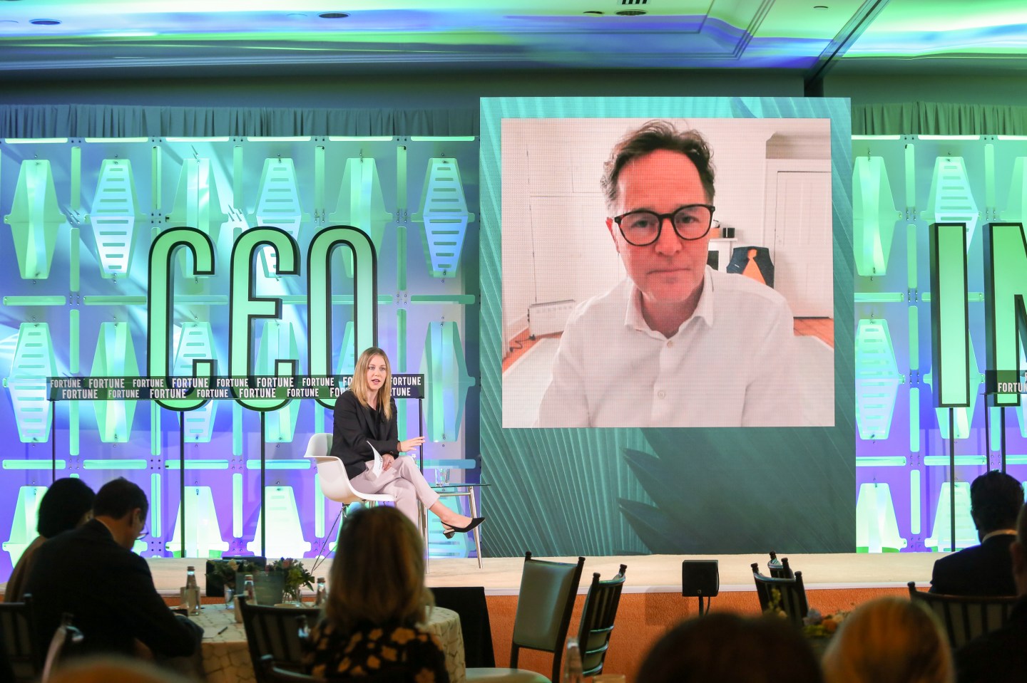 Fortune's Alyson Shontell sitting in a chair with her legs crossed next to Meta's Nick Clegg featured on screen wearing a white button down and glasses.