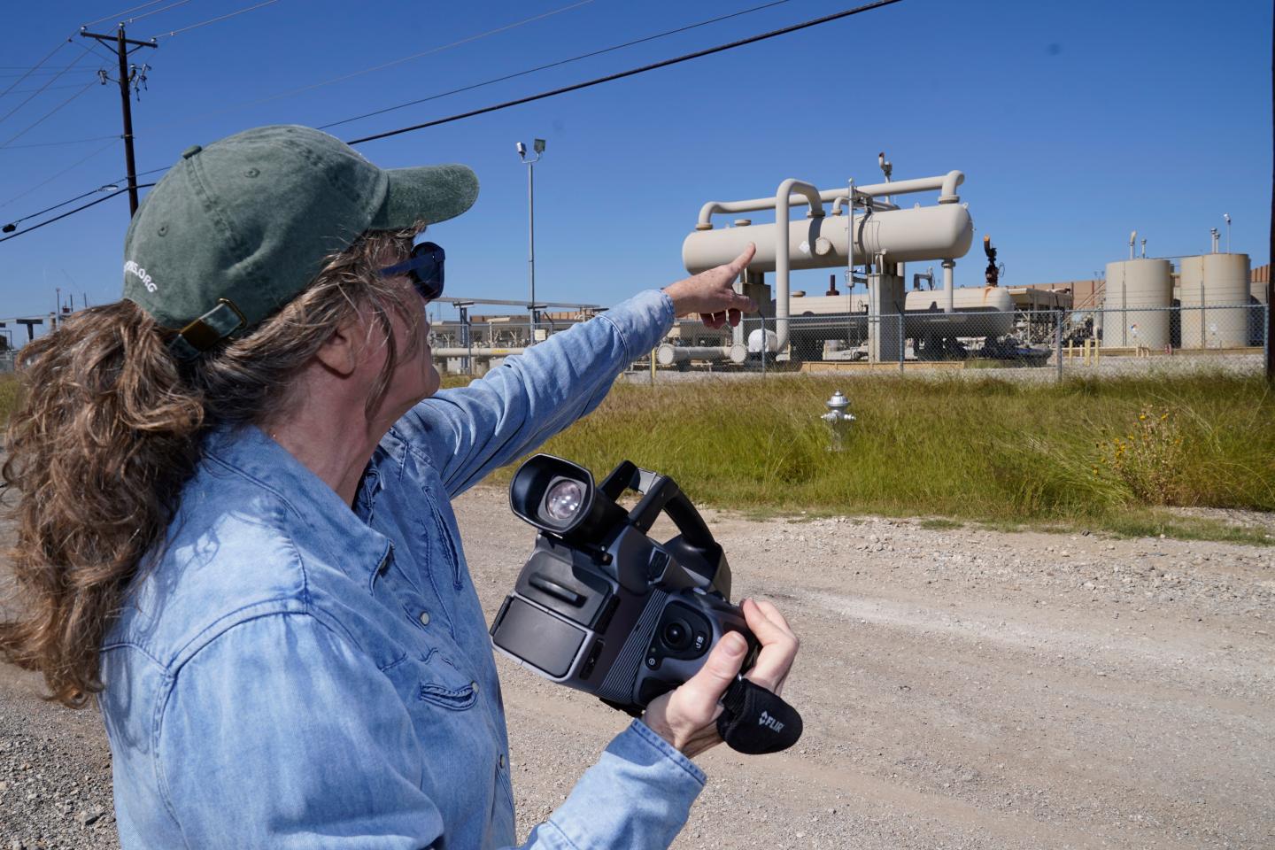 A woman points at tanks she says are leaking methane.