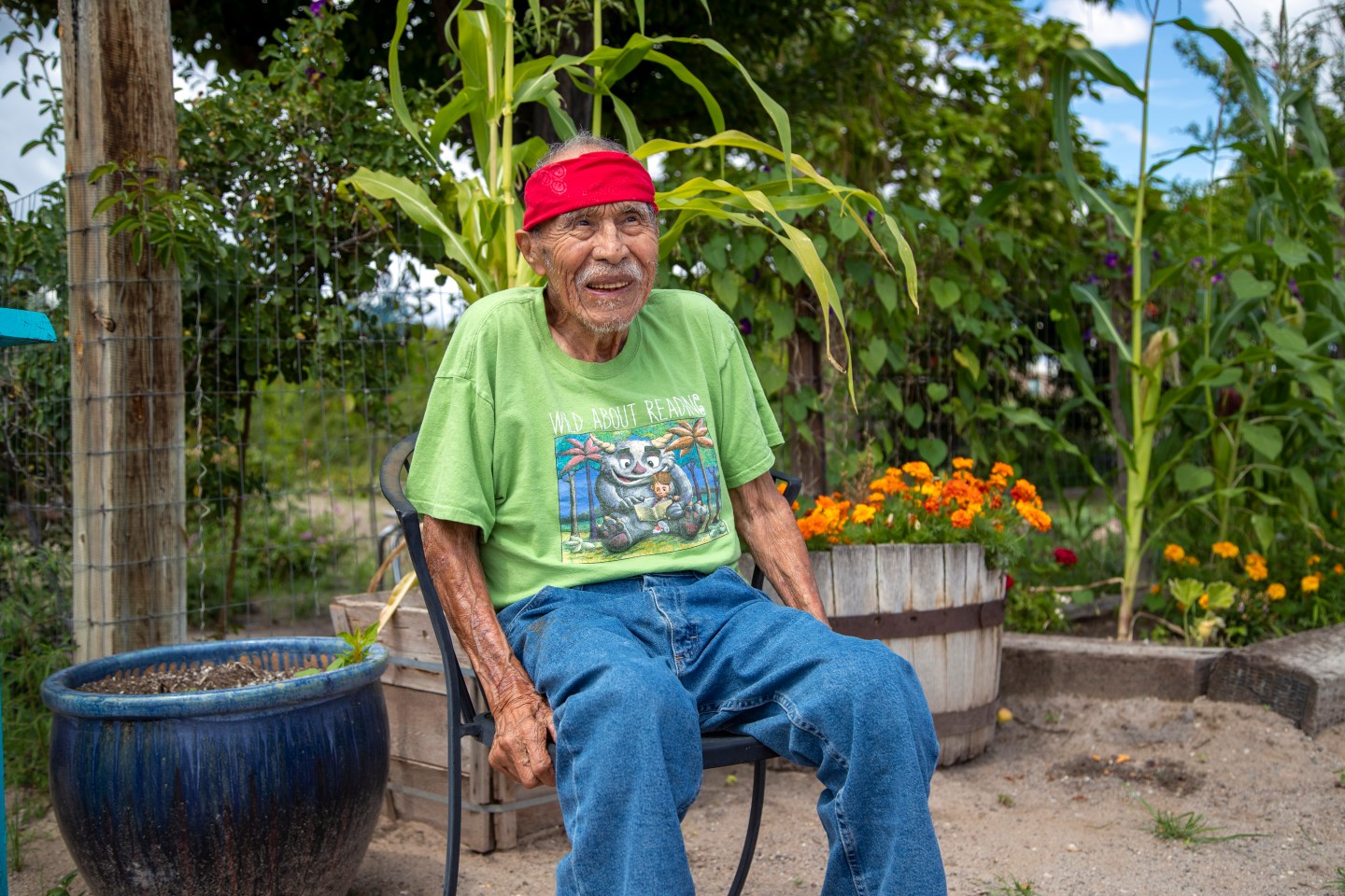 An elderly man sits on a chair.